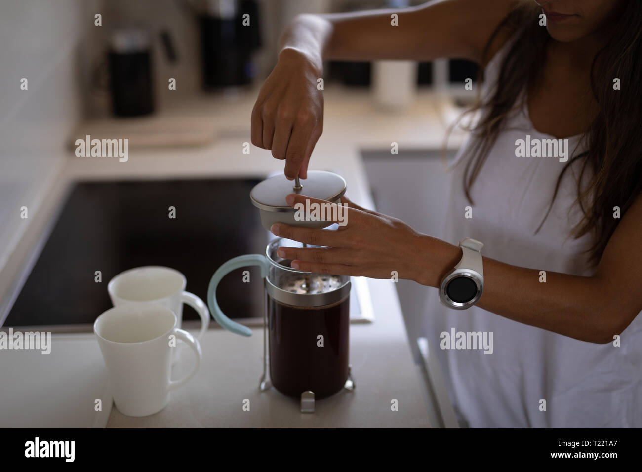 Frau, die Kaffee in der Kaffeemaschine in der Küche Stockfoto Frau, die Kaffee in der Kaffeemaschine in der Küche Stockfoto
