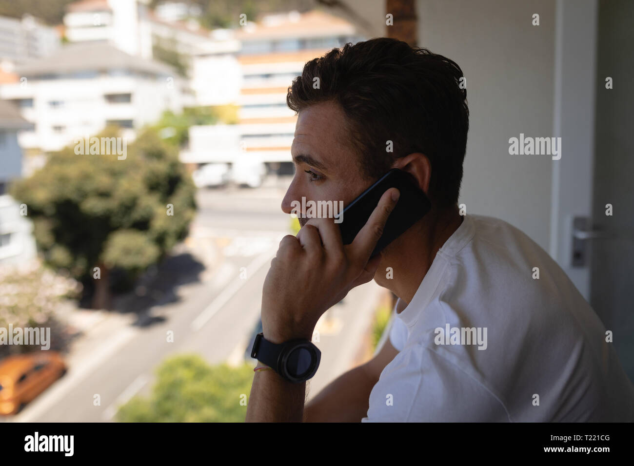 Mann Gespräch am Handy beim Stehen in der Balkon zu Hause Stockfoto