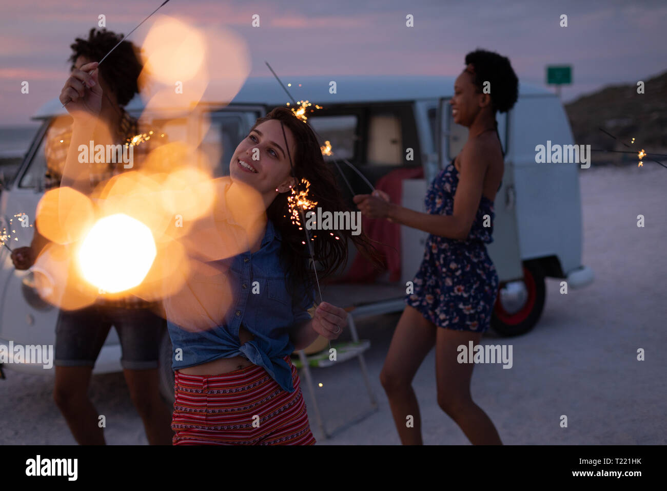 Gruppe von Freunden genießen am Strand, während Sie stehen in der Nähe des Wohnmobils mit funkelnden Blase Stockfoto