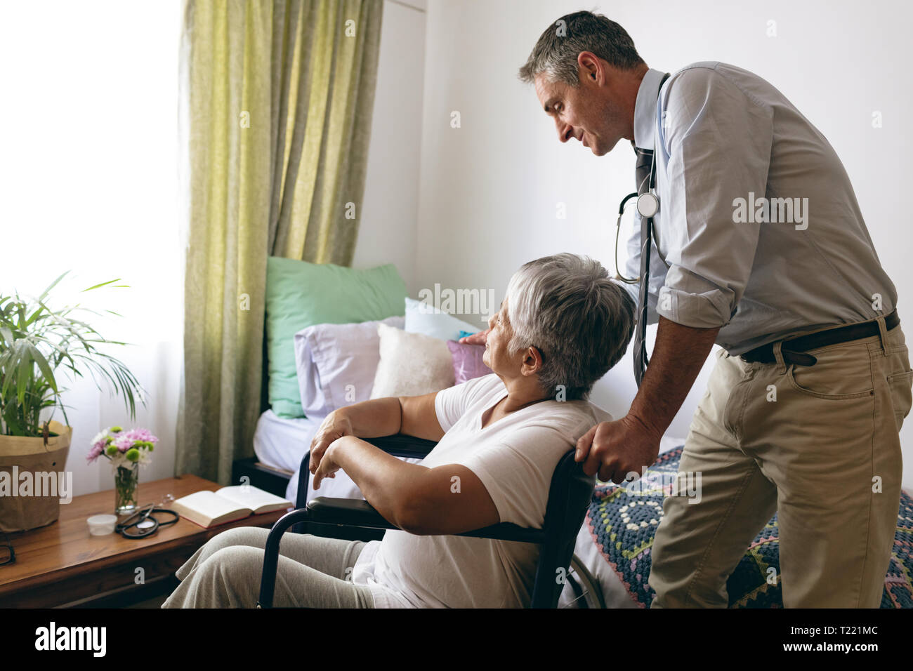Männlicher Arzt mit Patientin im Altenheim Interaktion Stockfoto