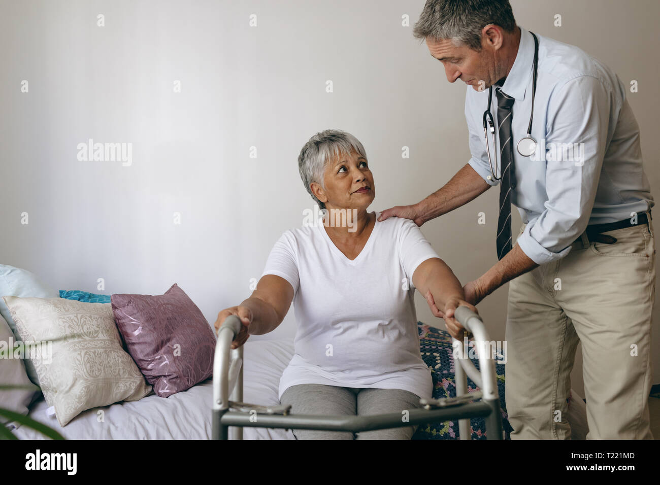 Männlicher Arzt helfen älteren weiblichen Patienten mit Walker zu gehen Stockfoto