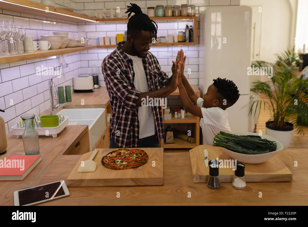 Vater High Five an seinen Sohn beim Schlichten kochen Stockfoto