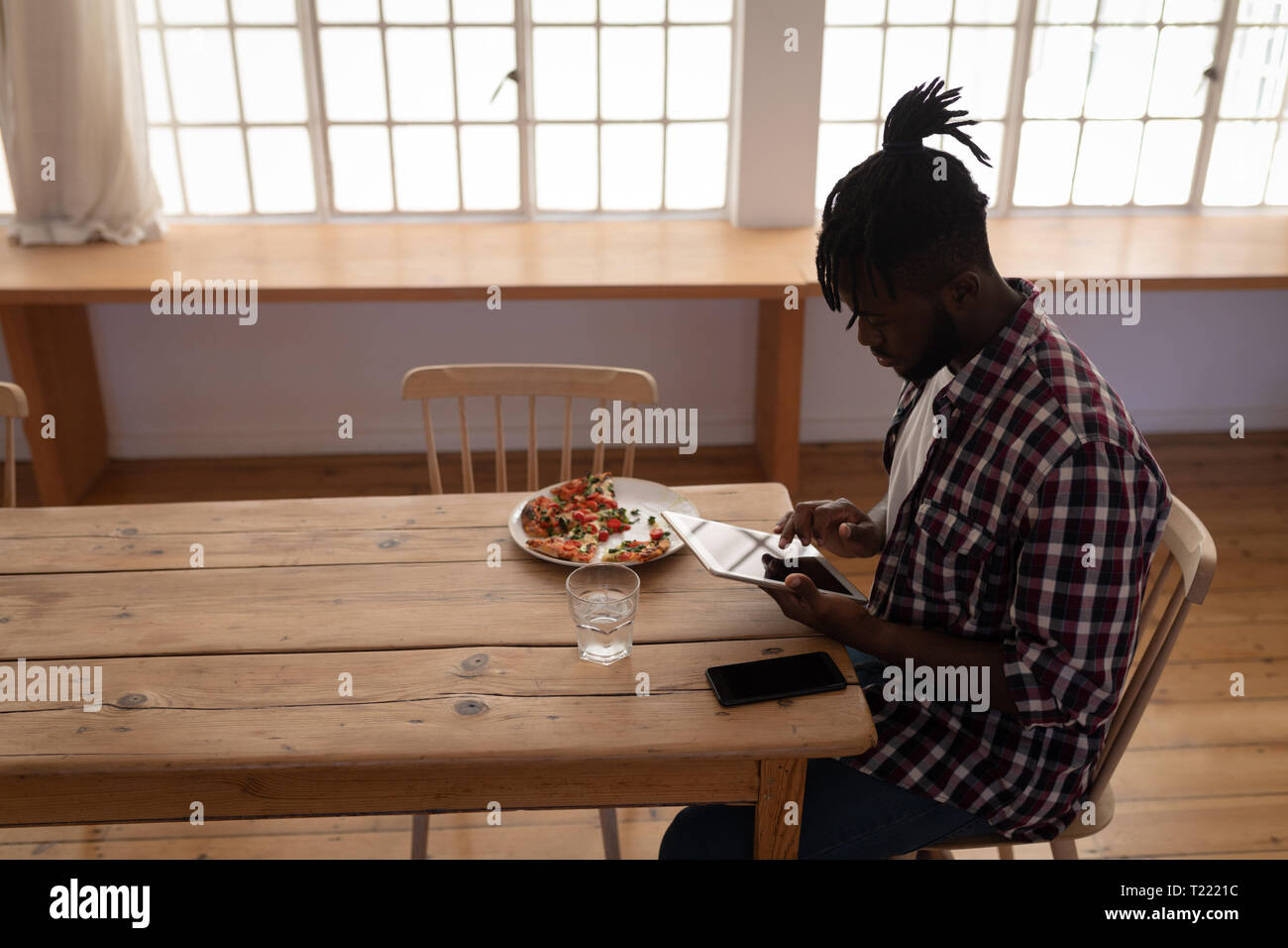 Mann mit digitalen Tablet während auf Stuhl zu Hause sitzen Stockfoto