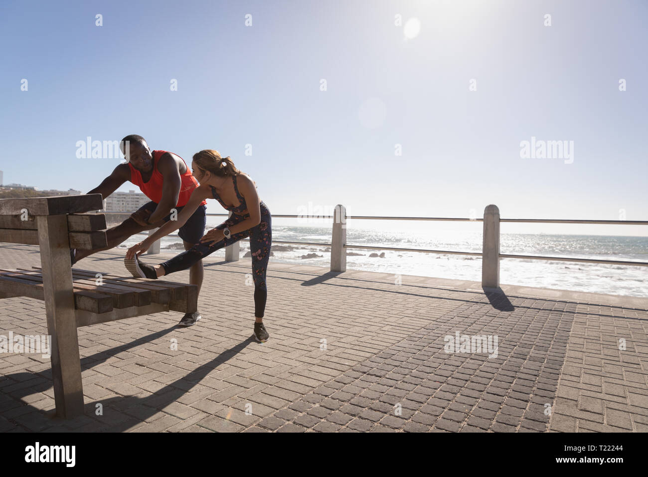 Junges Paar zu tun stretching Übung auf der Bank in der Nähe von Strand Stockfoto