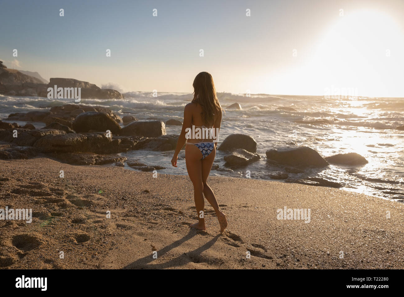 Schöne Frau zu Fuß am Strand an einem sonnigen Tag Stockfoto