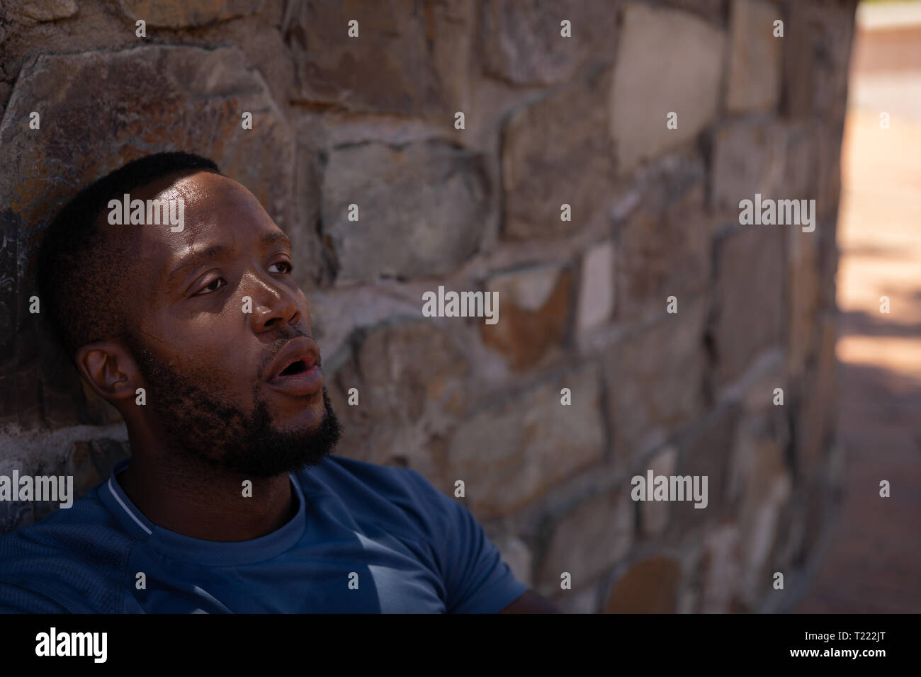 Man entspannende neben Wand an einem sonnigen Tag Stockfoto