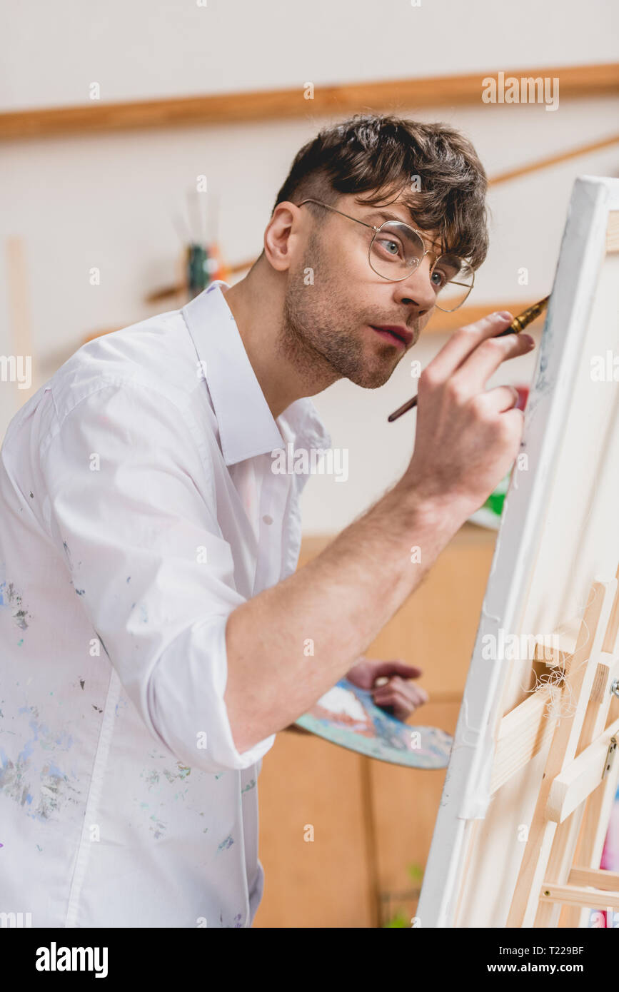 Stattliche artist in weißem Hemd und Brille Gemälde auf Leinwand Stockfoto