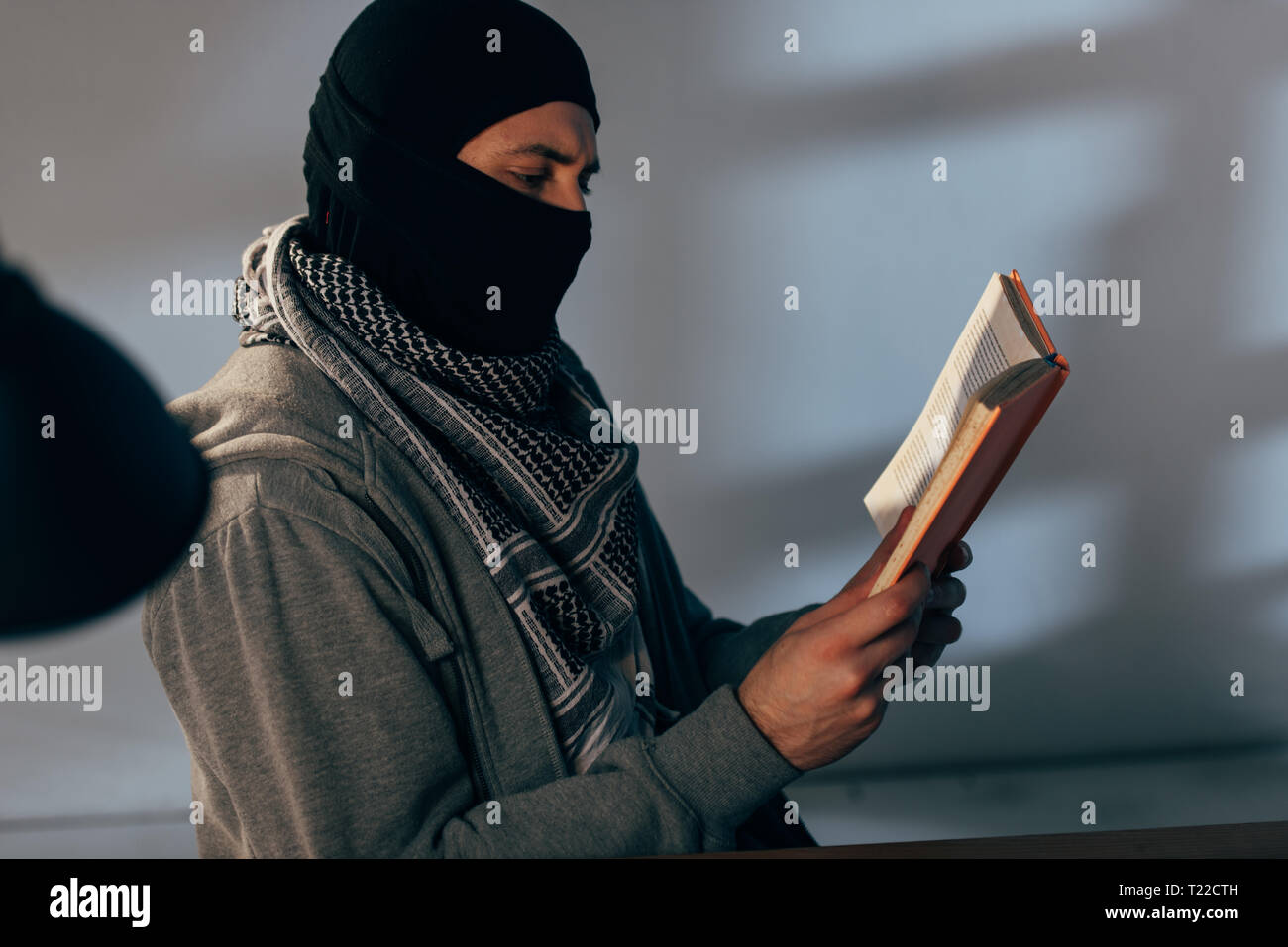 Terrorist in schwarze Maske und kufiya Schal Buch lesen Stockfoto