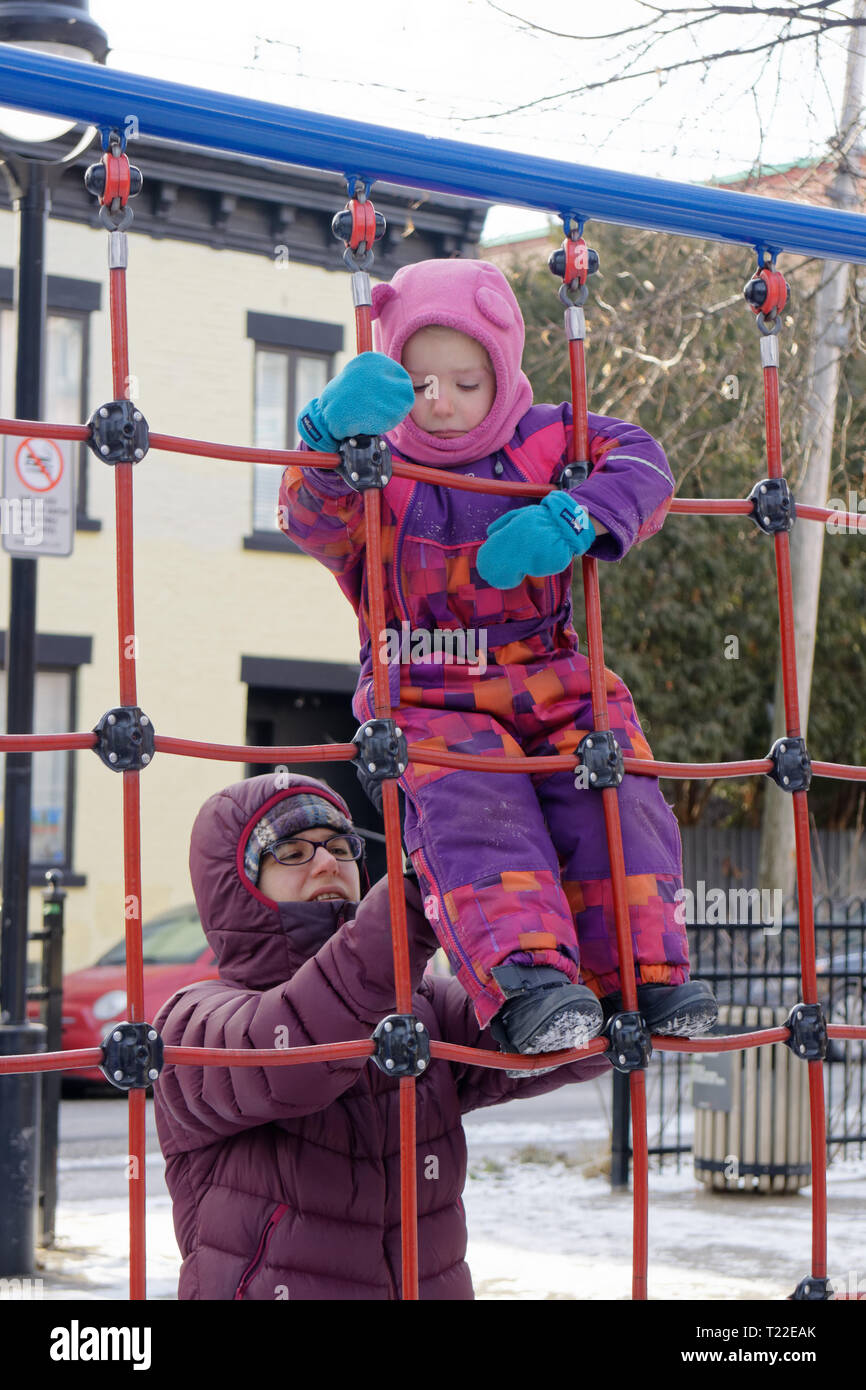 Eine Mutter mit ihrer kleinen Tochter (4 Jahre alt) auf einem Klettergerüst in Quebec im Winter Stockfoto