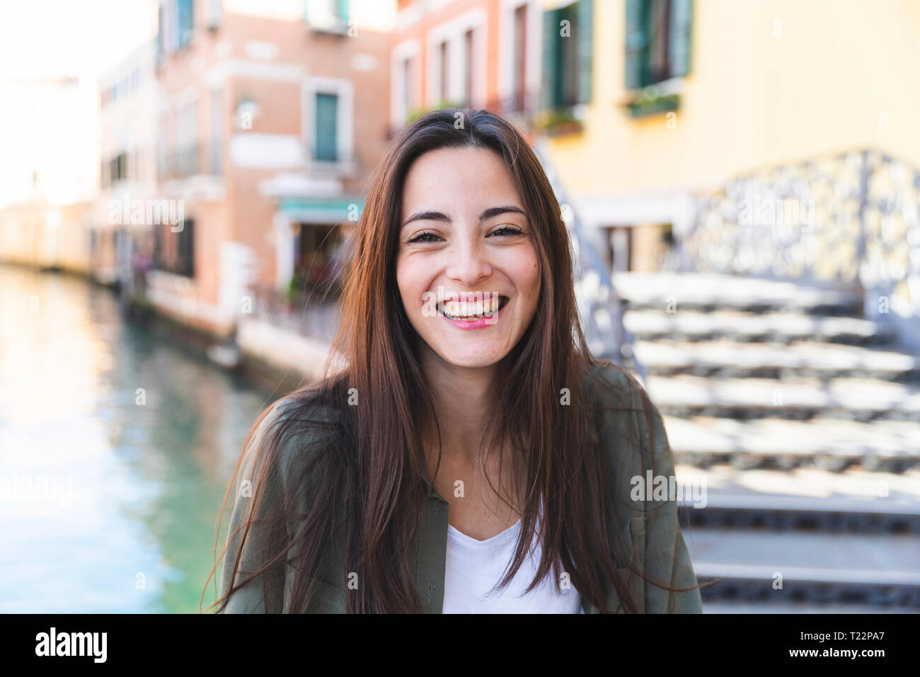 Italien, Venedig, Porträt der Lachende junge Frau in der Stadt mit Canal im Hintergrund Stockfoto