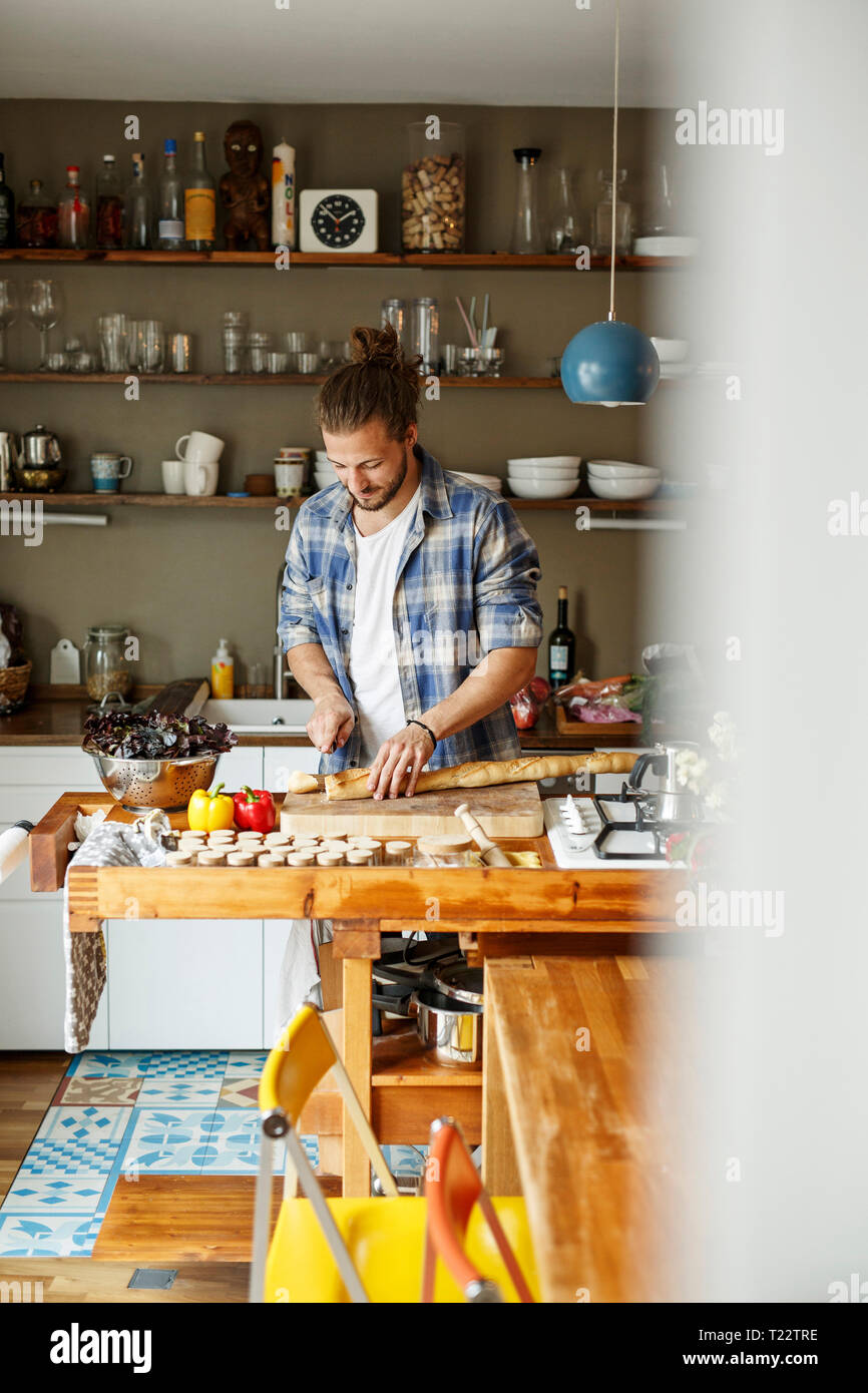 Junger Mann essen zu Hause vorbereiten, schneiden Brot Stockfoto