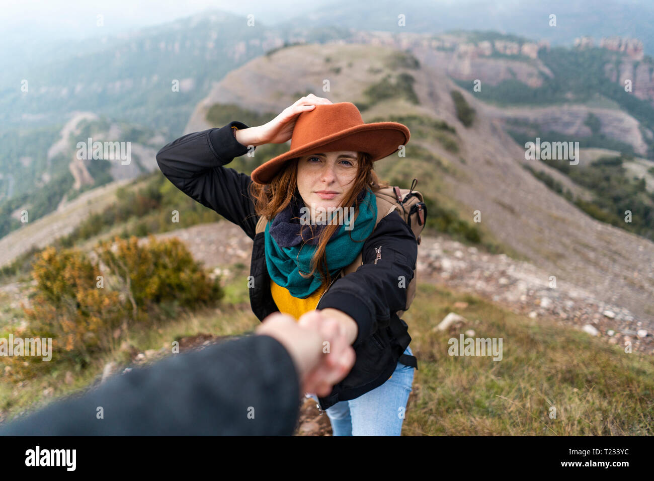 Frau mit Hut, die auf Berg, Holding an Hand des Menschen Stockfoto