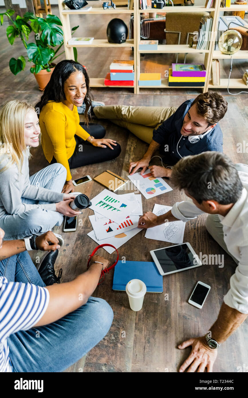 Happy Business Team sitzen auf dem Boden diskutieren Dokumente in loft Büro Stockfoto