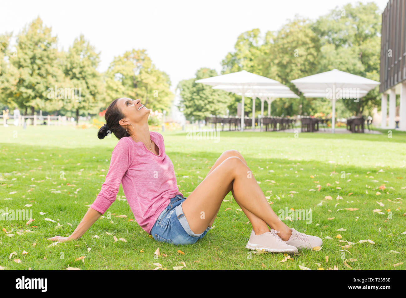 Reife Frau sitzt auf einer Wiese im Sommer bis in den Himmel suchen Stockfoto