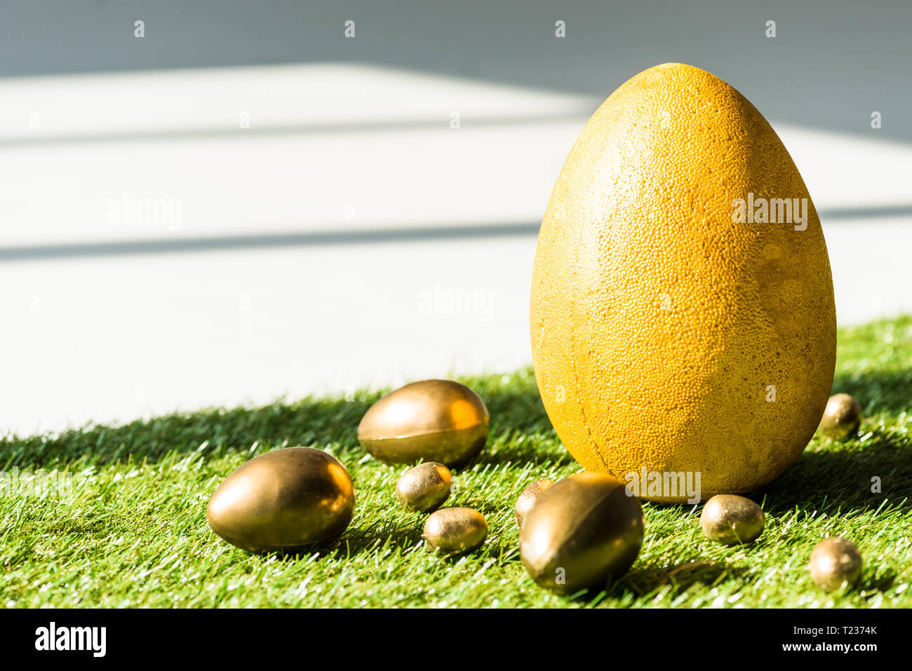 Gelbe Straußenei und goldene Ostereier auf grünem Gras Oberfläche Stockfoto