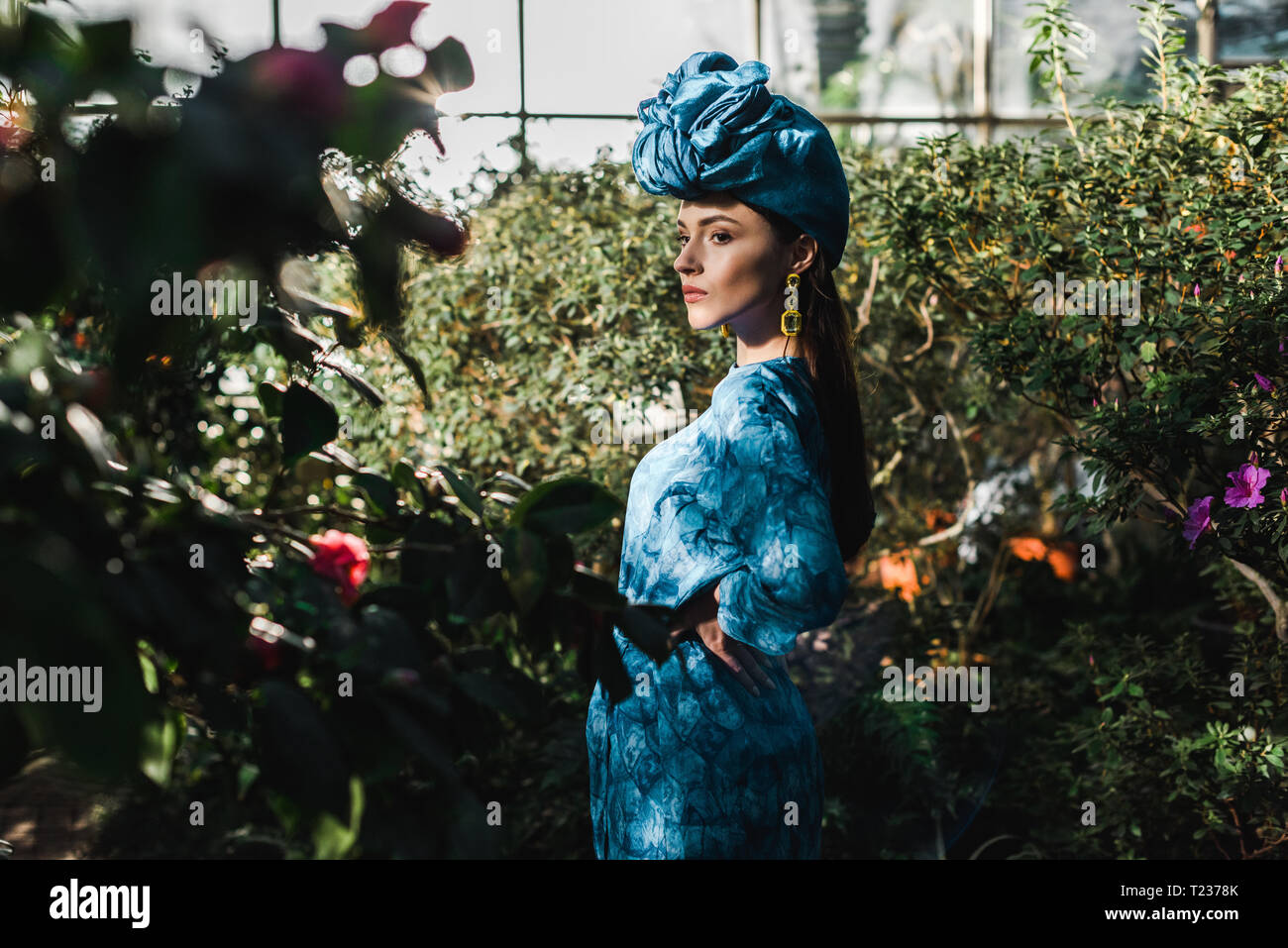 Wunderschöne junge Frau im blauen Kleid und Turban in Orangerie Stockfoto
