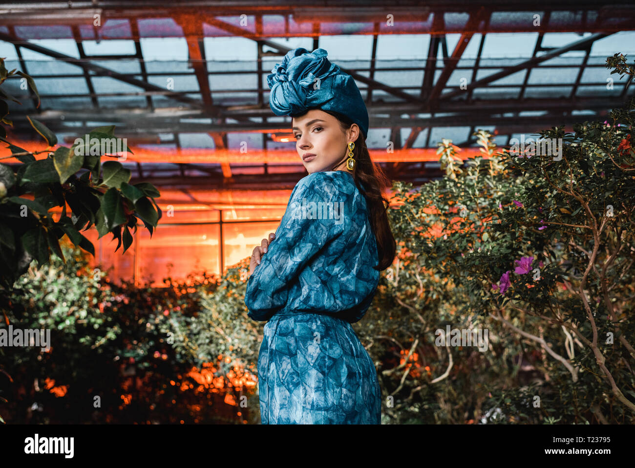 Wunderschöne junge Frau im blauen Kleid in Turban in Orangerie Stockfoto