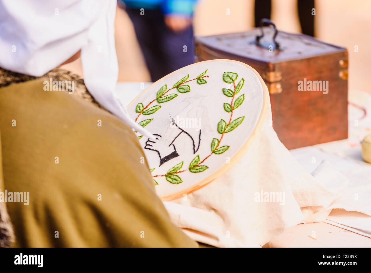 Junge Frau Näherin nähen eine einfache Zeichnung, getarnt als mittelalterliche in ein traditionelles Handwerk Kinder Ausstellung. Stockfoto