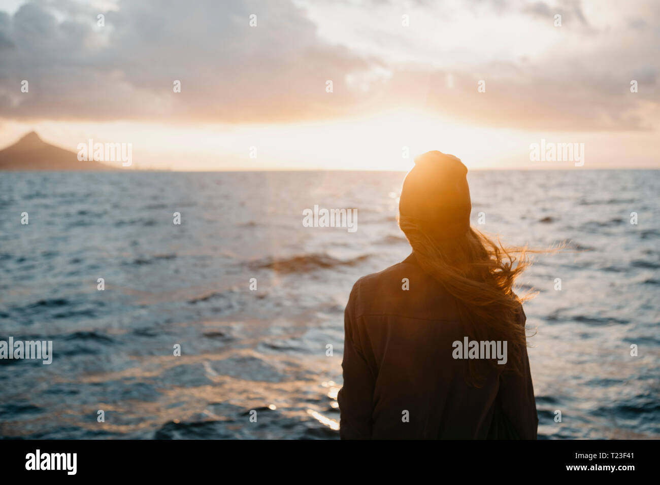 Südafrika, junge Frau mit wollmütze während der Bootsfahrt bei Sonnenuntergang Stockfoto