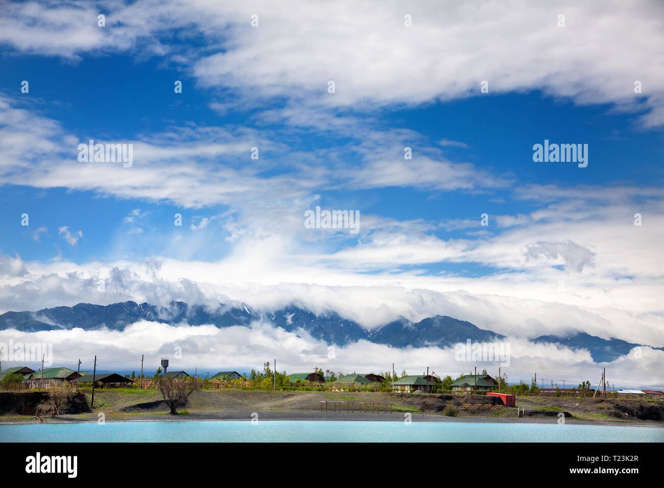 See in der Nähe und das Dorf in der Nähe von bewölkt Berge im Blue Sky in Kasachstan und Zentralasien Stockfoto