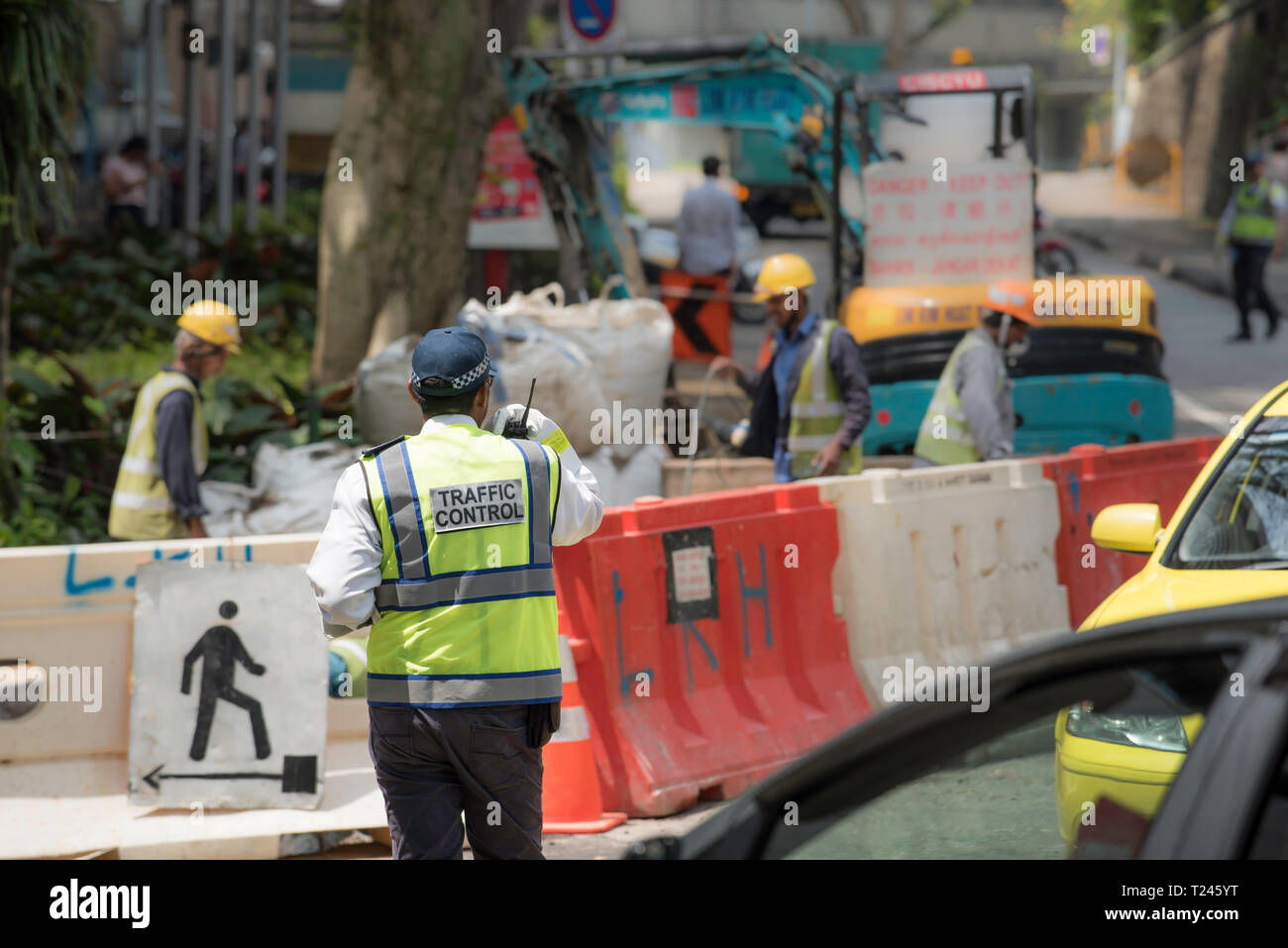 Eine Flugsicherung Person führt Autos um eine Straße Baustelle im Zentrum von Singapur Stockfoto