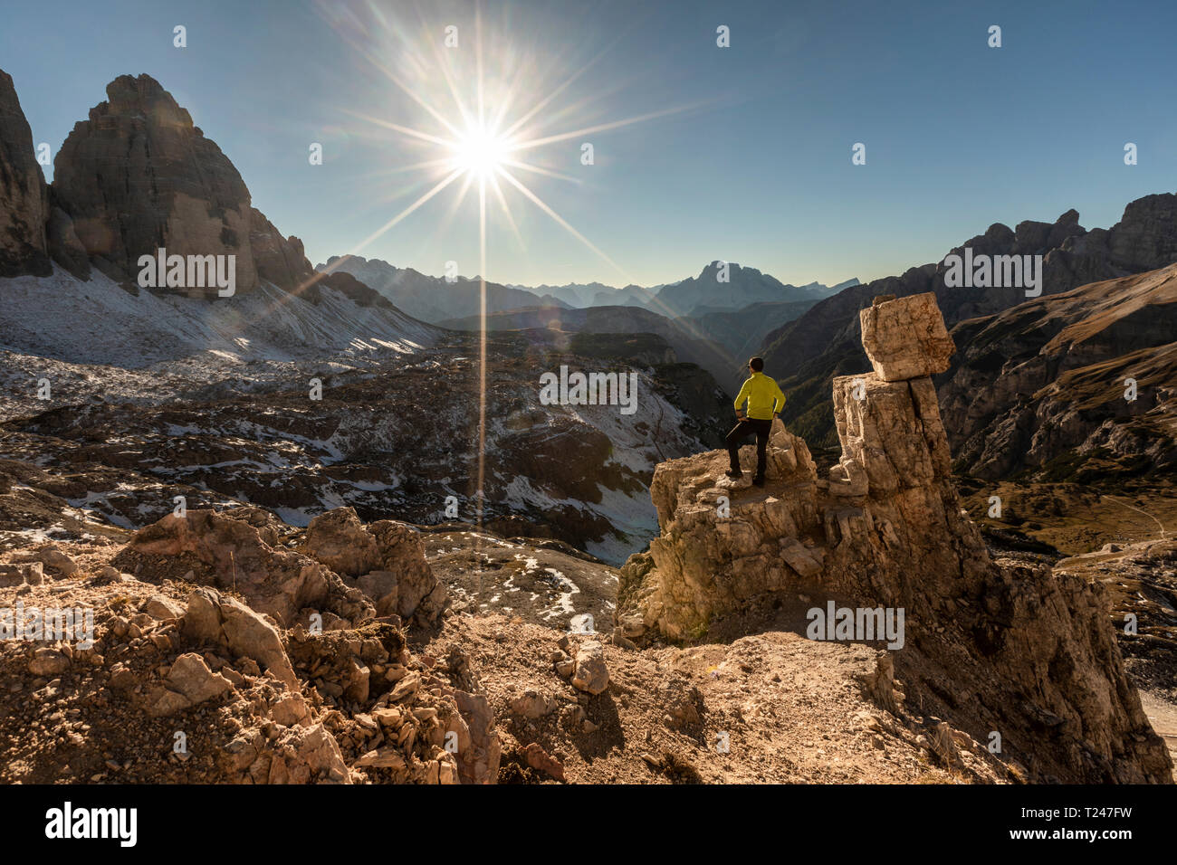Italien, Tre Cime di Lavaredo, man wandern und Blick auf das Tal mit Gipfeln und Sonne über den Horizont Stockfoto