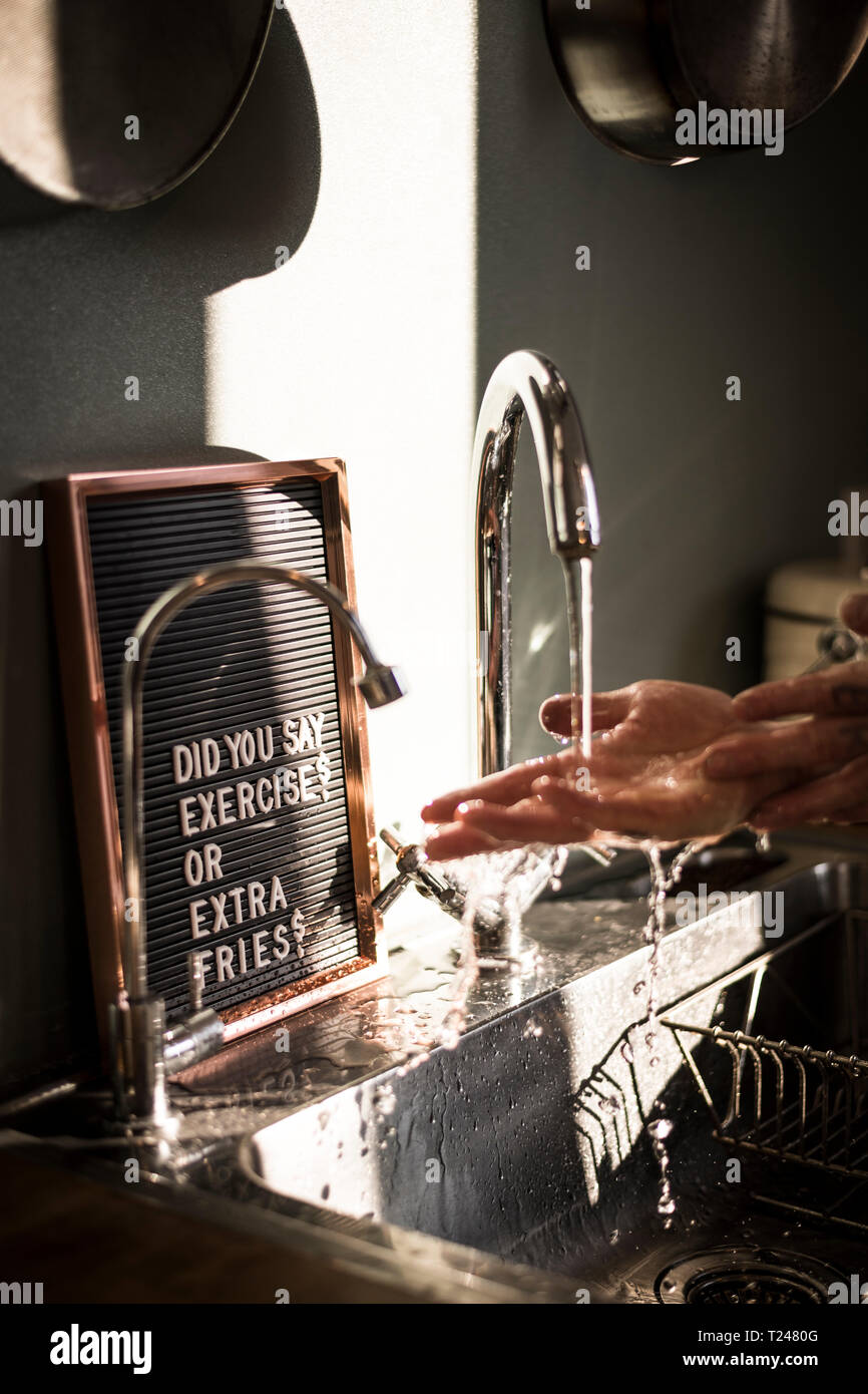 Vorstand mit lustigen Text an der Spüle, wo ein Mann seine Hände waschen Stockfoto