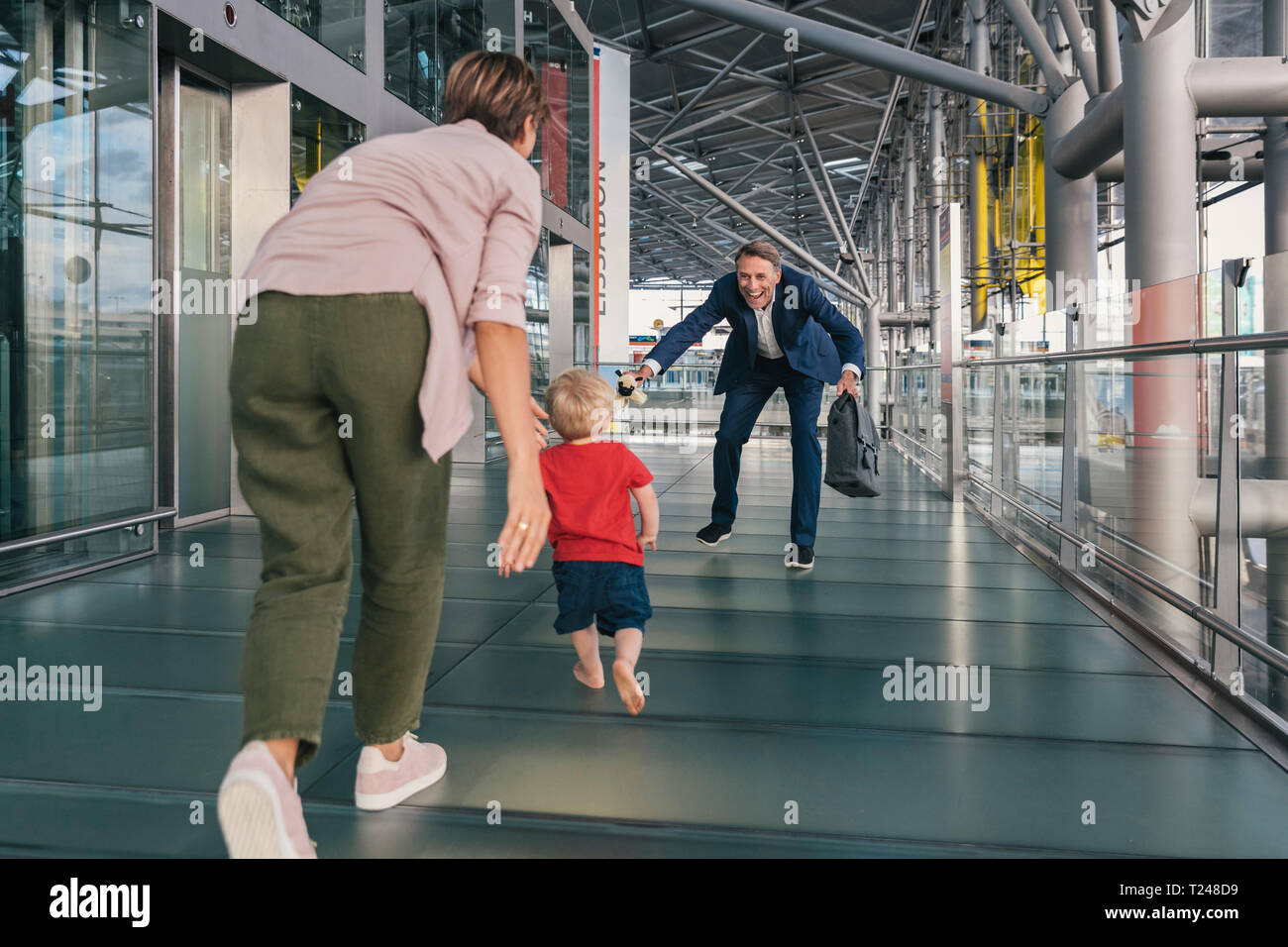 Glückliches Kind in die Arme der reisenden Geschäftsmann am Flughafen läuft Stockfoto