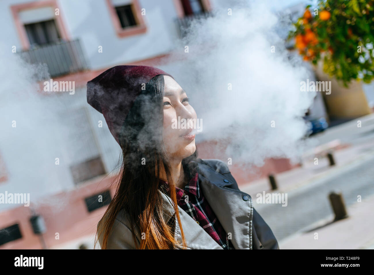 Junge Frau bläst Rauch aus elektronische Zigarette Stockfoto