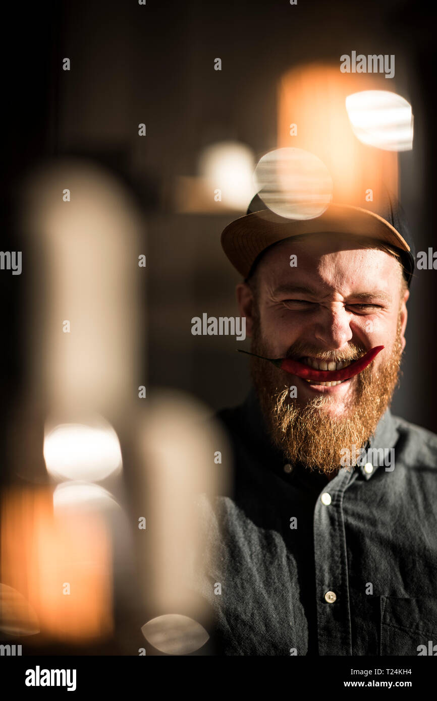 Laughing Man Beißen eines roten Chili pod Stockfoto