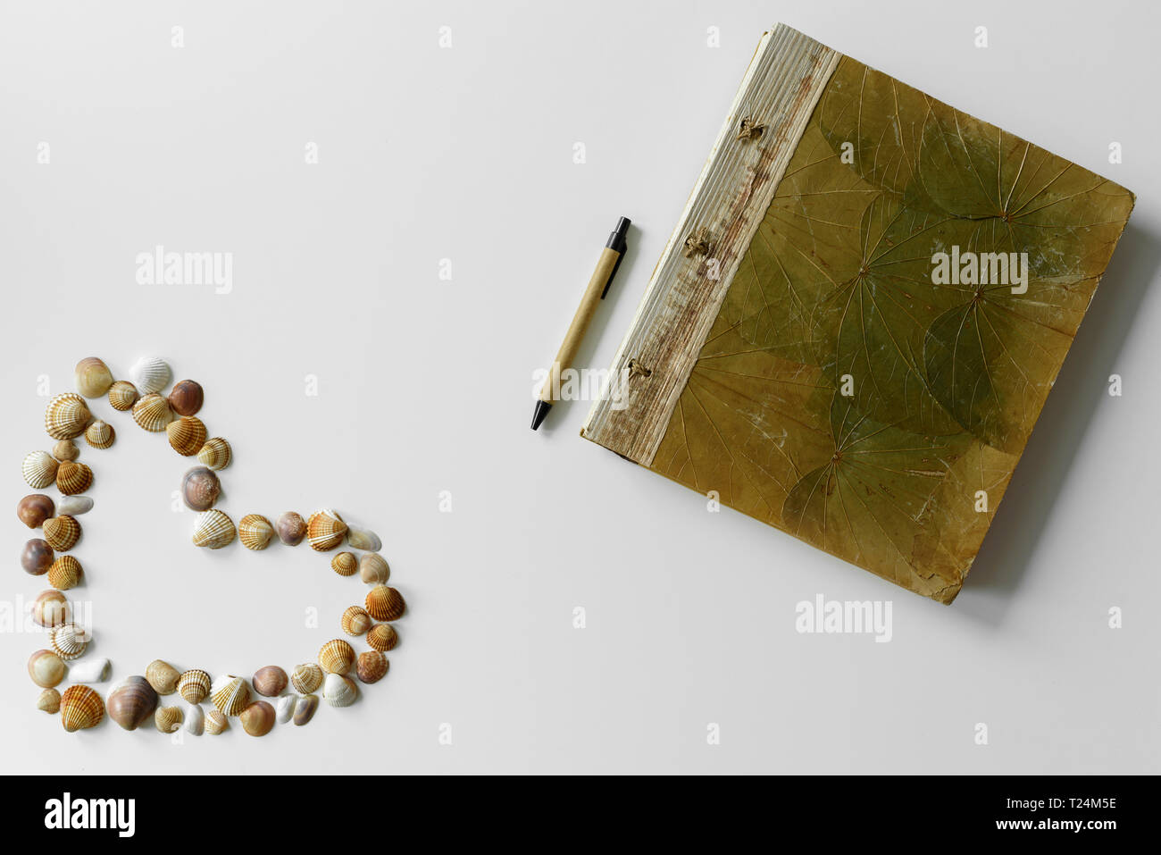 Süße sommer herz aus Muscheln auf weißem Hintergrund und Ferienhäuser Tagebuch mit Blatt und Stift erstellt. Stockfoto