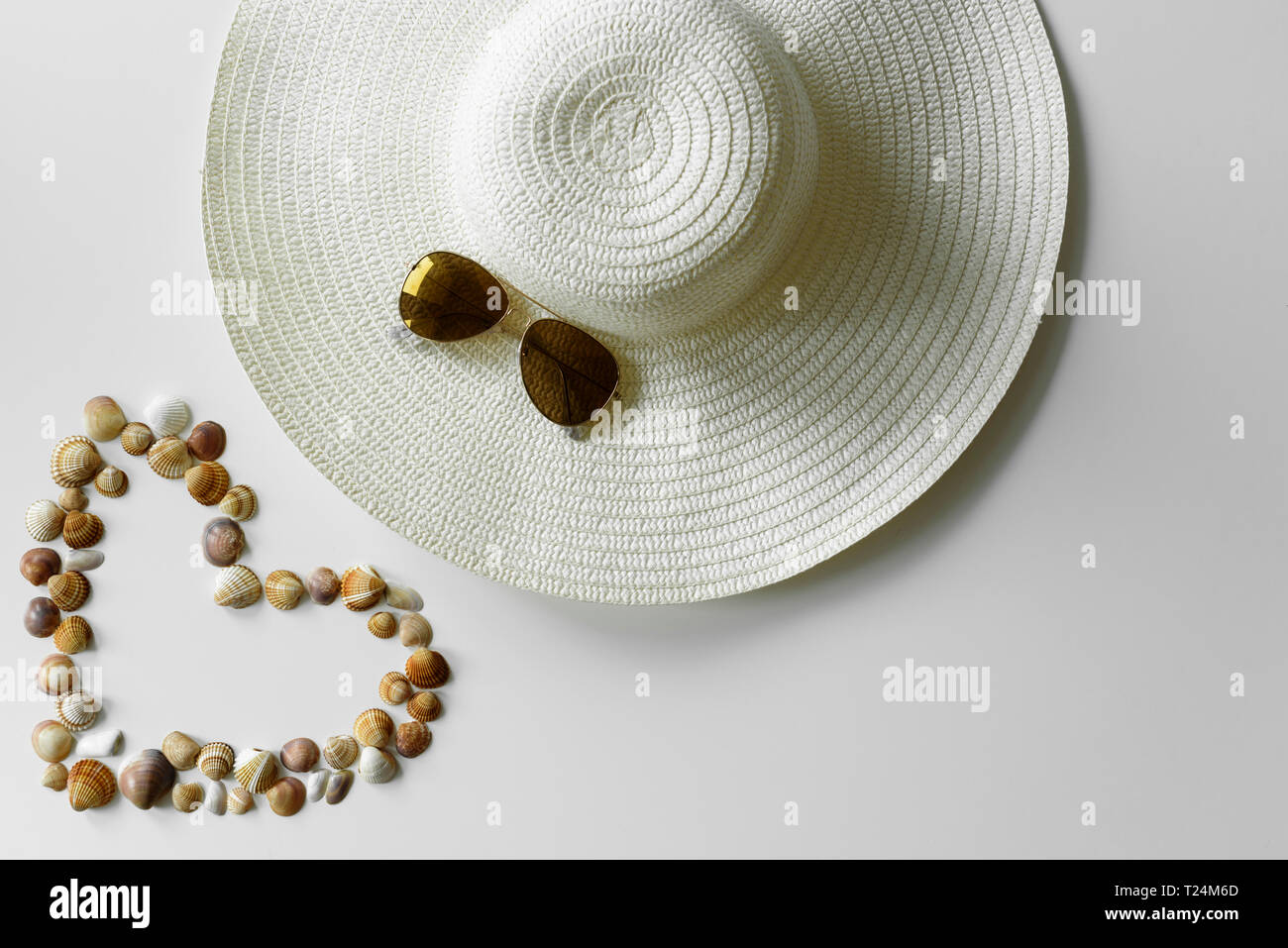 Sommer mode Deko von Herzförmige seashells konzipiert, sun Strohhut und Pilotenbrillen. Ferienhäuser Hintergrund. Stockfoto