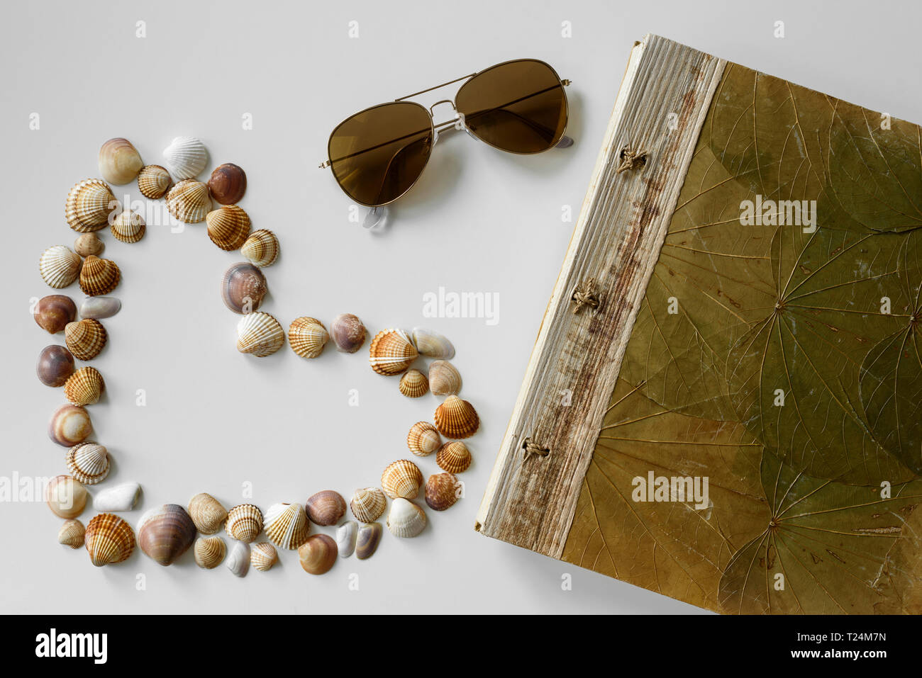 Sommer set-up von aviator Sonnenbrille erstellt, Ferienhäuser Notebook und herzförmige Seashells. Stockfoto