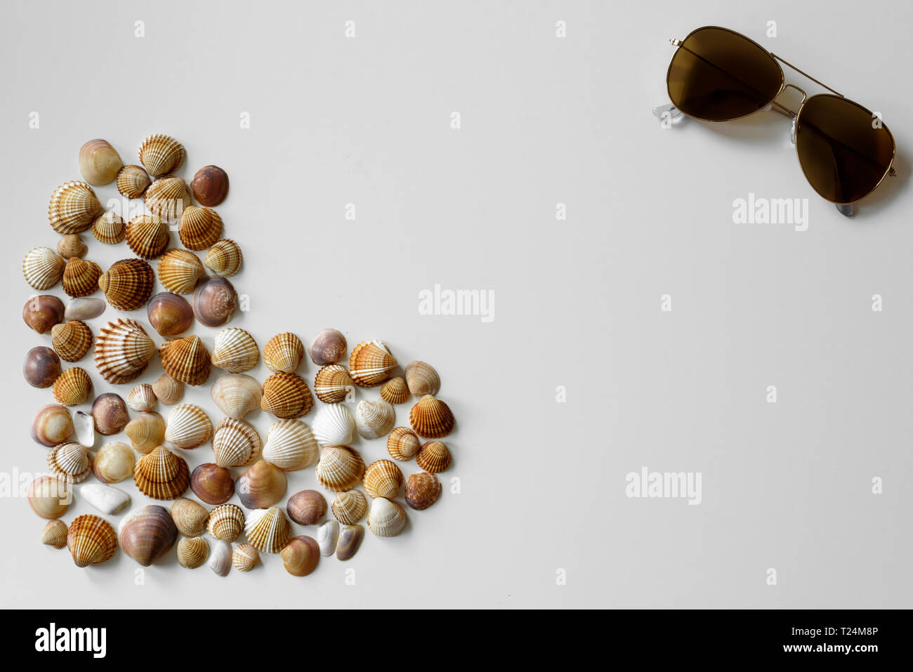 Minimalistischer Sommer Dekoration aus vollem Herzen Muscheln und aviator Sonnenbrille mit Kopie Raum zwischen diesen Objekten auf weißem Hintergrund erstellt. Stockfoto