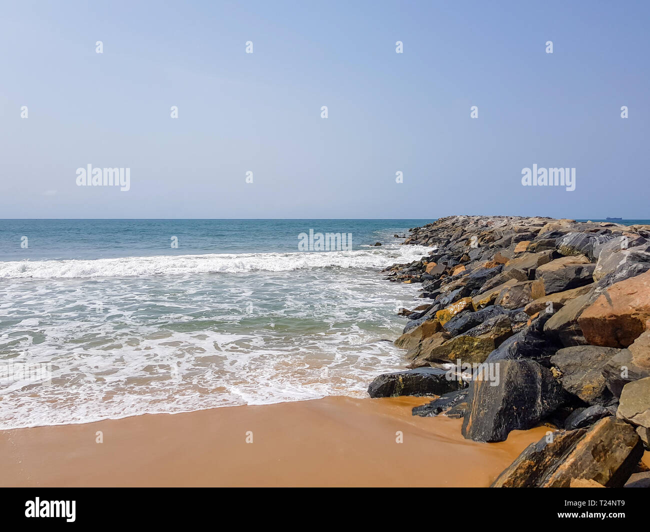 Wellen plätschern auf Felsen in einen wellenbrecher an einem sonnigen Tag am Strand. Schutz der Küstengebiete und der Küste Befestigungsanlage. Stockfoto