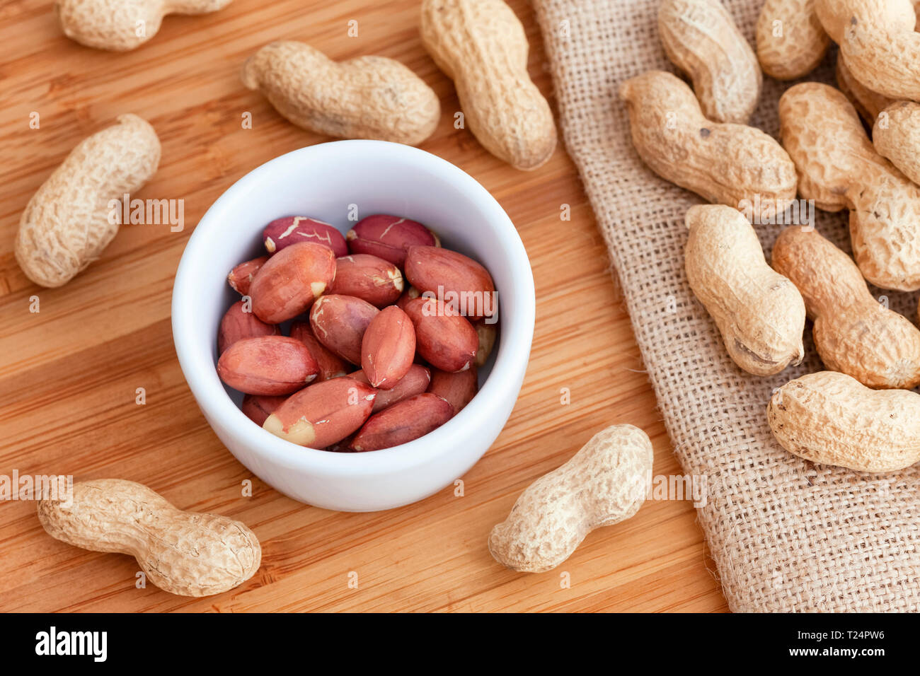 Die Erdnüsse ohne Schale in eine Schüssel durch Erdnüsse in der Schale umgeben. Close Up. Stockfoto