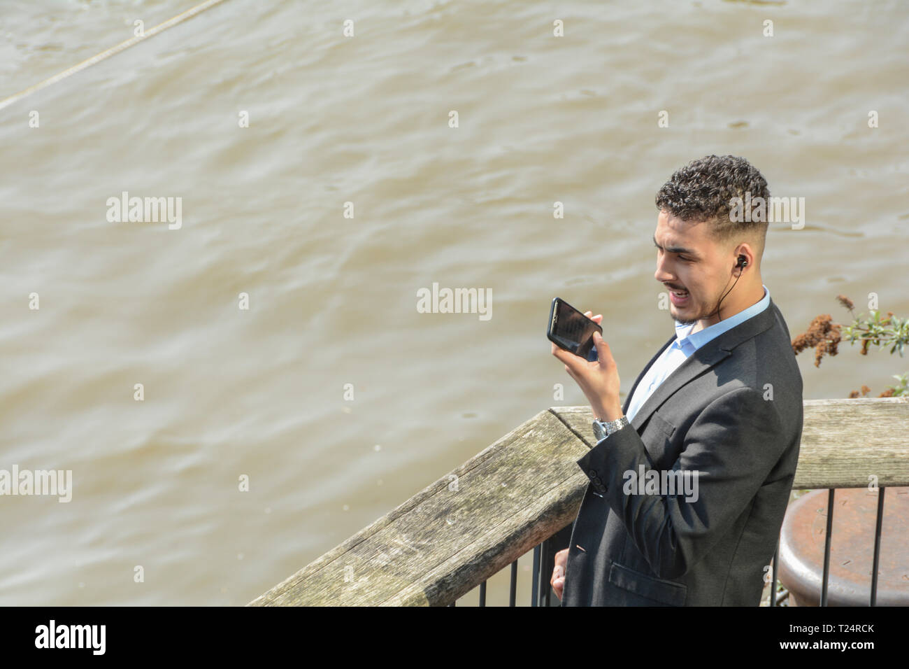 Ein junger Geschäftsmann Grimassen während auf sein Mobiltelefon in London, Großbritannien Stockfoto