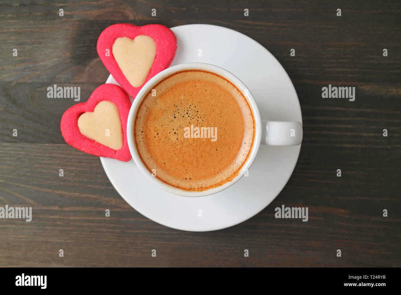 Flach Foto von einer Espressomaschine mit zwei herzförmige Plätzchen auf dunkelbraunen hölzernen Tisch serviert. Stockfoto