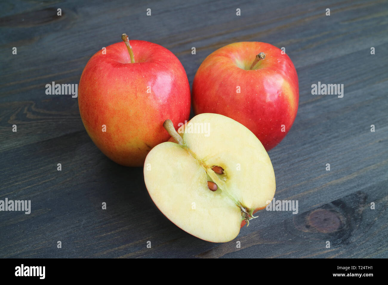 Vibrant red apple ganze Früchte und Querschnitt auf dunklen Holztisch Stockfoto