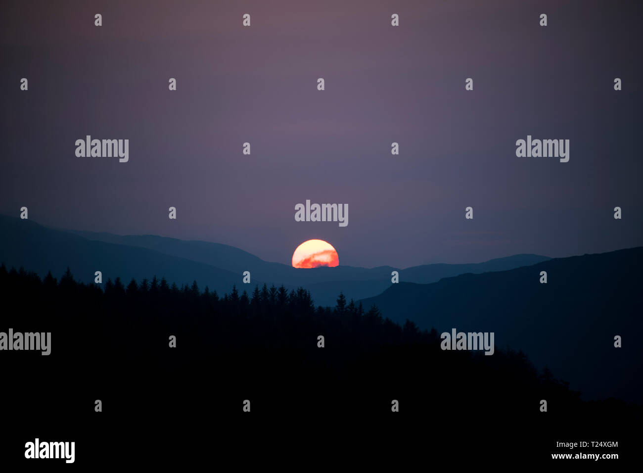 Die Sonne hinter Hügeln, Schottland, Großbritannien Stockfoto