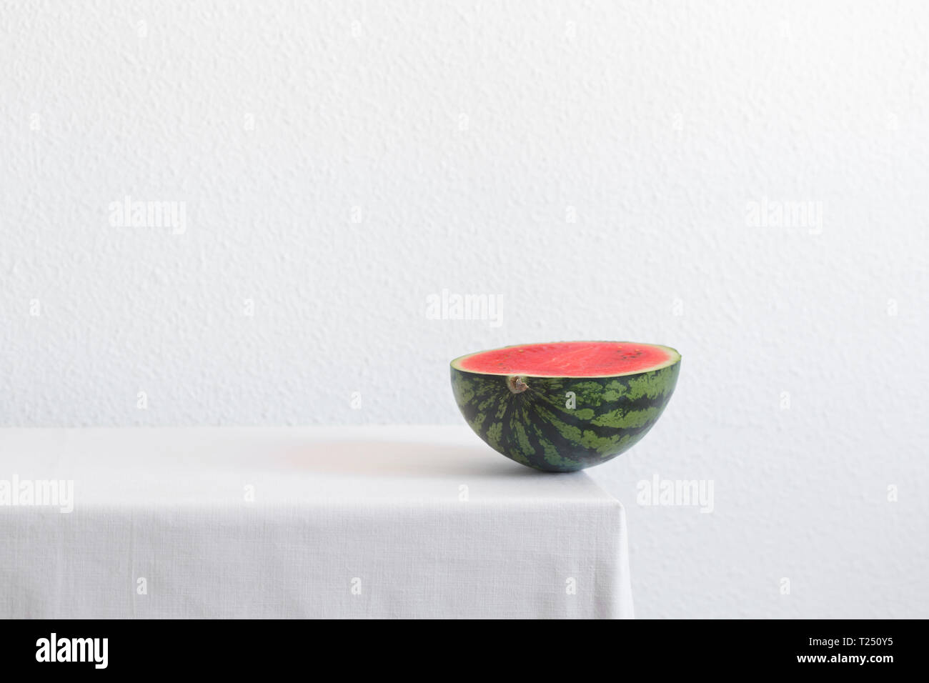 Die Hälfte der Wassermelone auf einem weißen Tisch mit kopieren. Kreative noch Leben Stockfoto