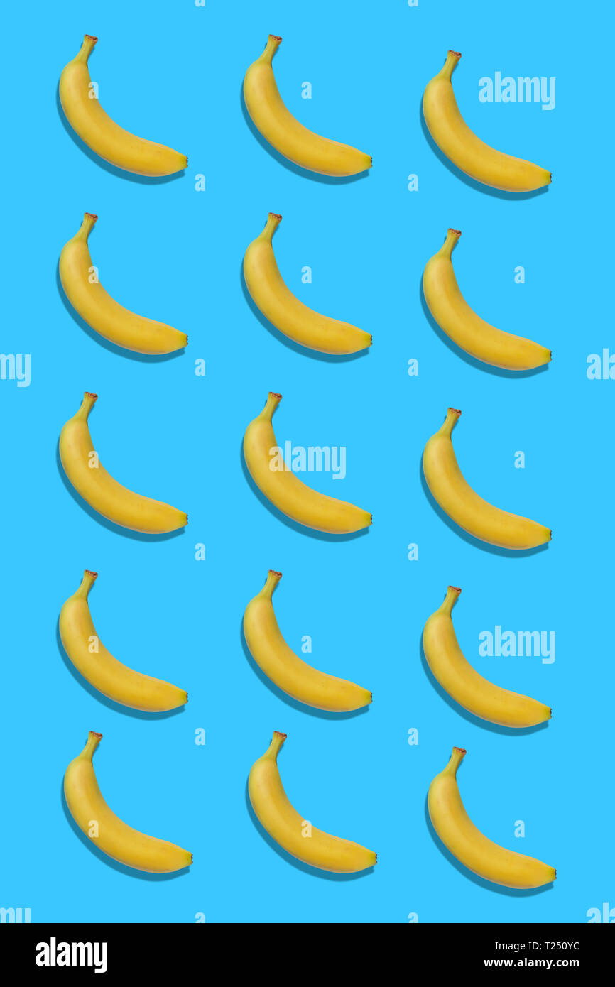 Gelbe Bananen auf blauem Hintergrund mit einem Schatten. Vertikale Ausrichtung Stockfoto