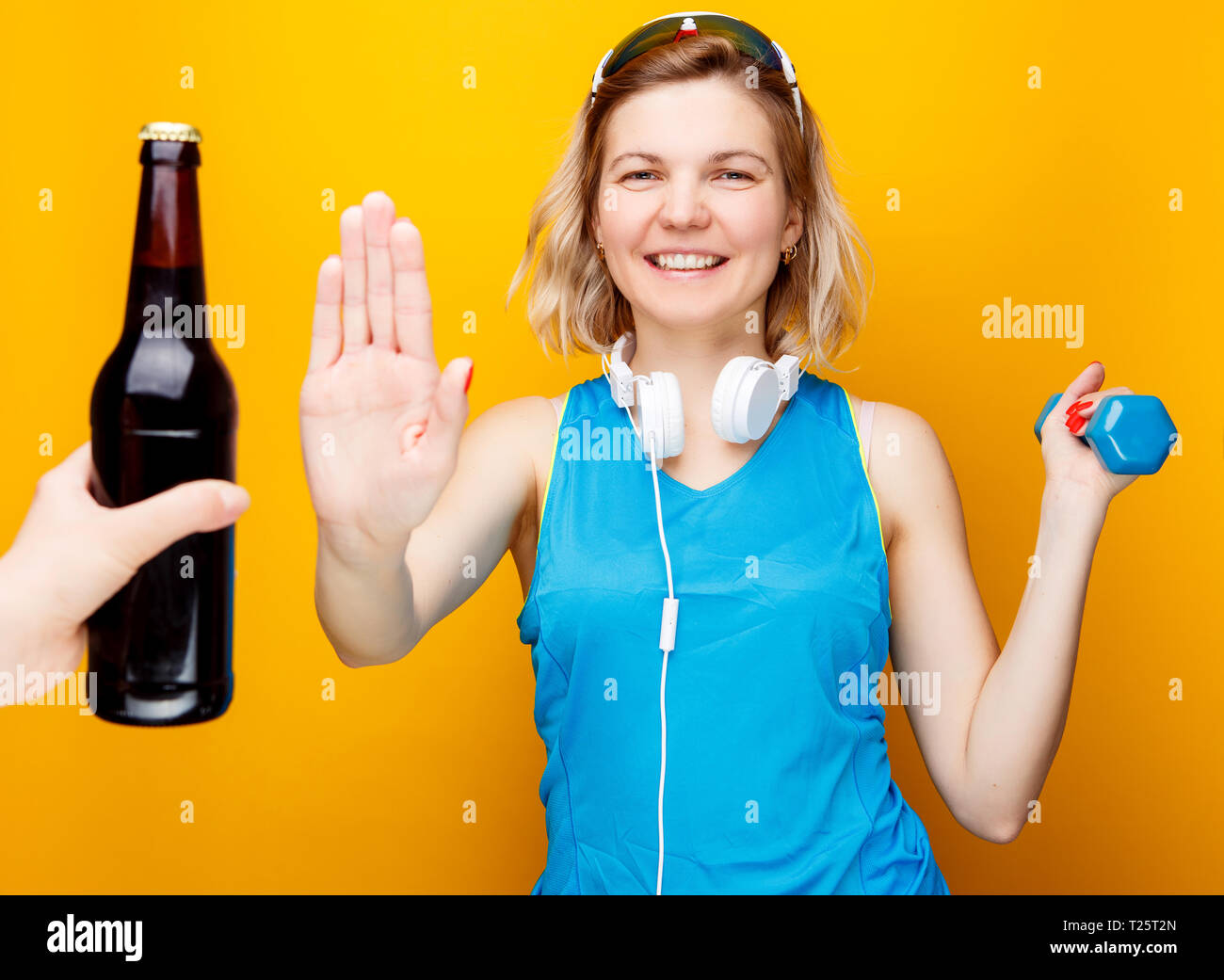 Sportliche Mädchen in Kopfhörer mit hantel in der Hand in Hand mit der  Flasche Bier Stockfotografie - Alamy