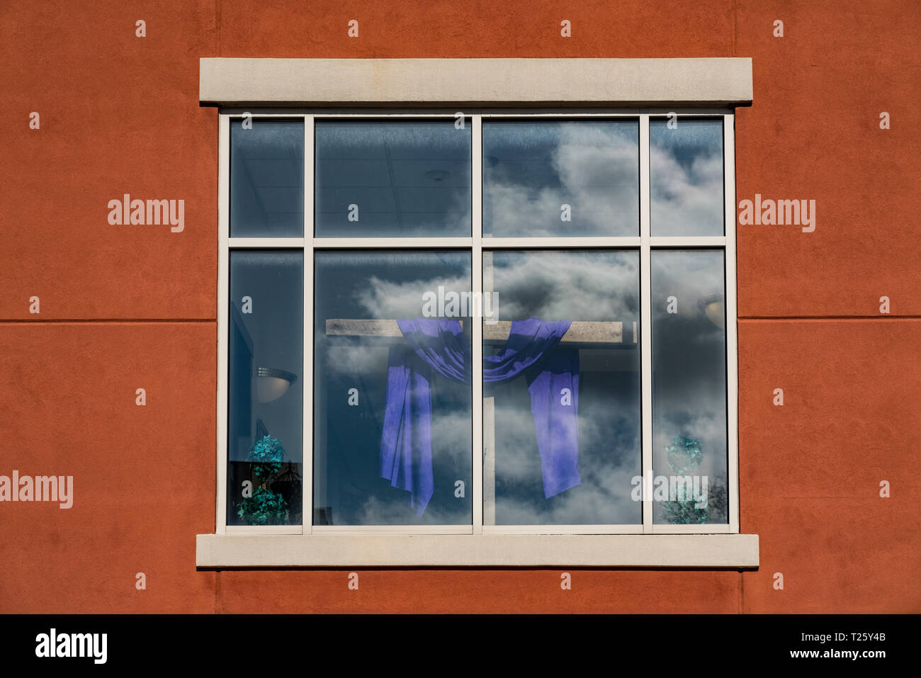 Holzkreuz mit lila Tuch für die Fastenzeit und Ostern im Fenster der Kirche Stockfoto