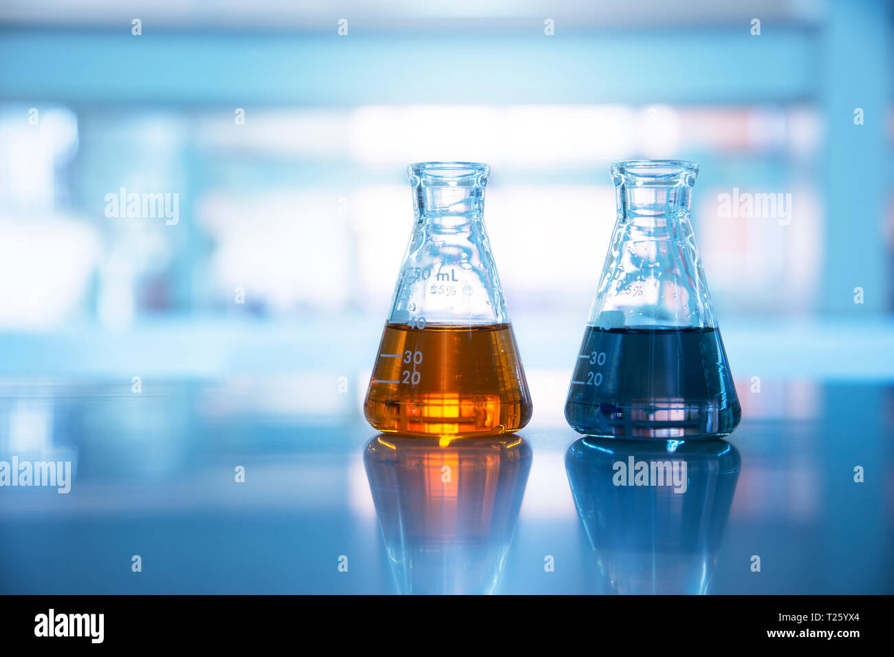 Zwei Glaskolben mit orange und schwarz Lösung in der chemischen Wissenschaft Labor Hintergrund Stockfoto