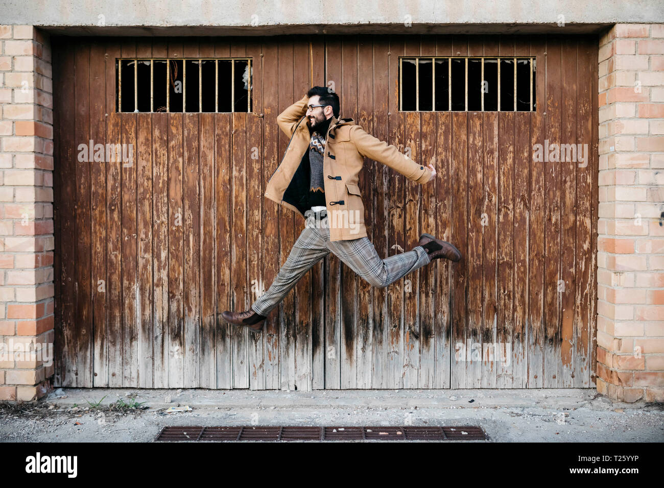 Spanien, Igualada, glücklicher Mann springen Mid-air auf heruntergekommenen hölzerne Tor Stockfoto