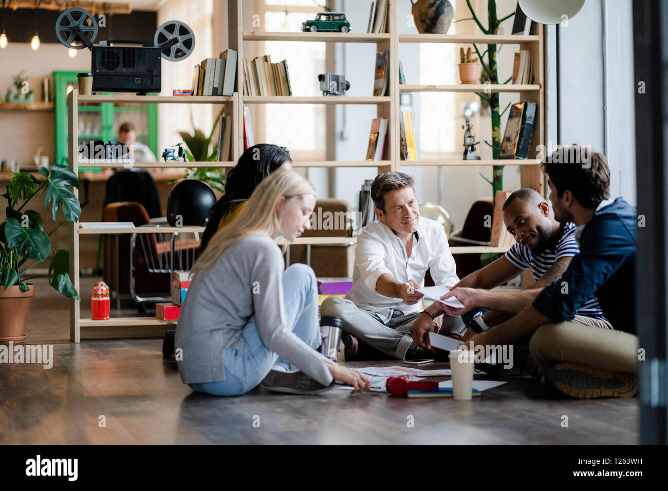 Business Team sitzen auf dem Boden diskutieren Dokumente in loft Büro Stockfoto