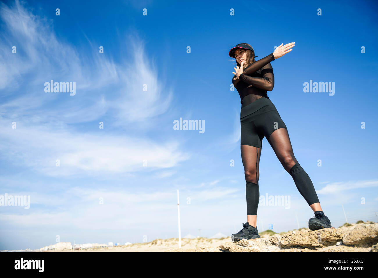 Sportliche Frau, die auf Stein Wand tun strecthing Übung Stockfoto