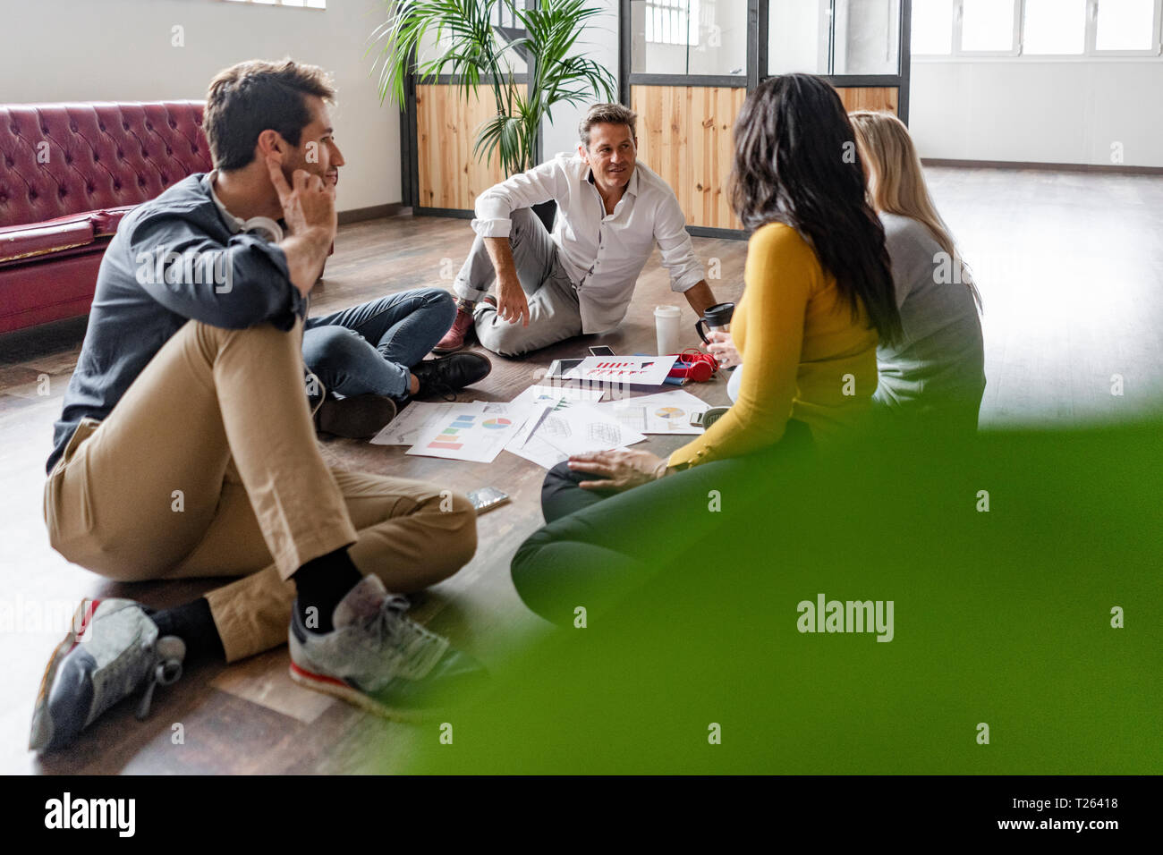 Business Team sitzen auf dem Boden diskutieren Dokumente in loft Büro Stockfoto