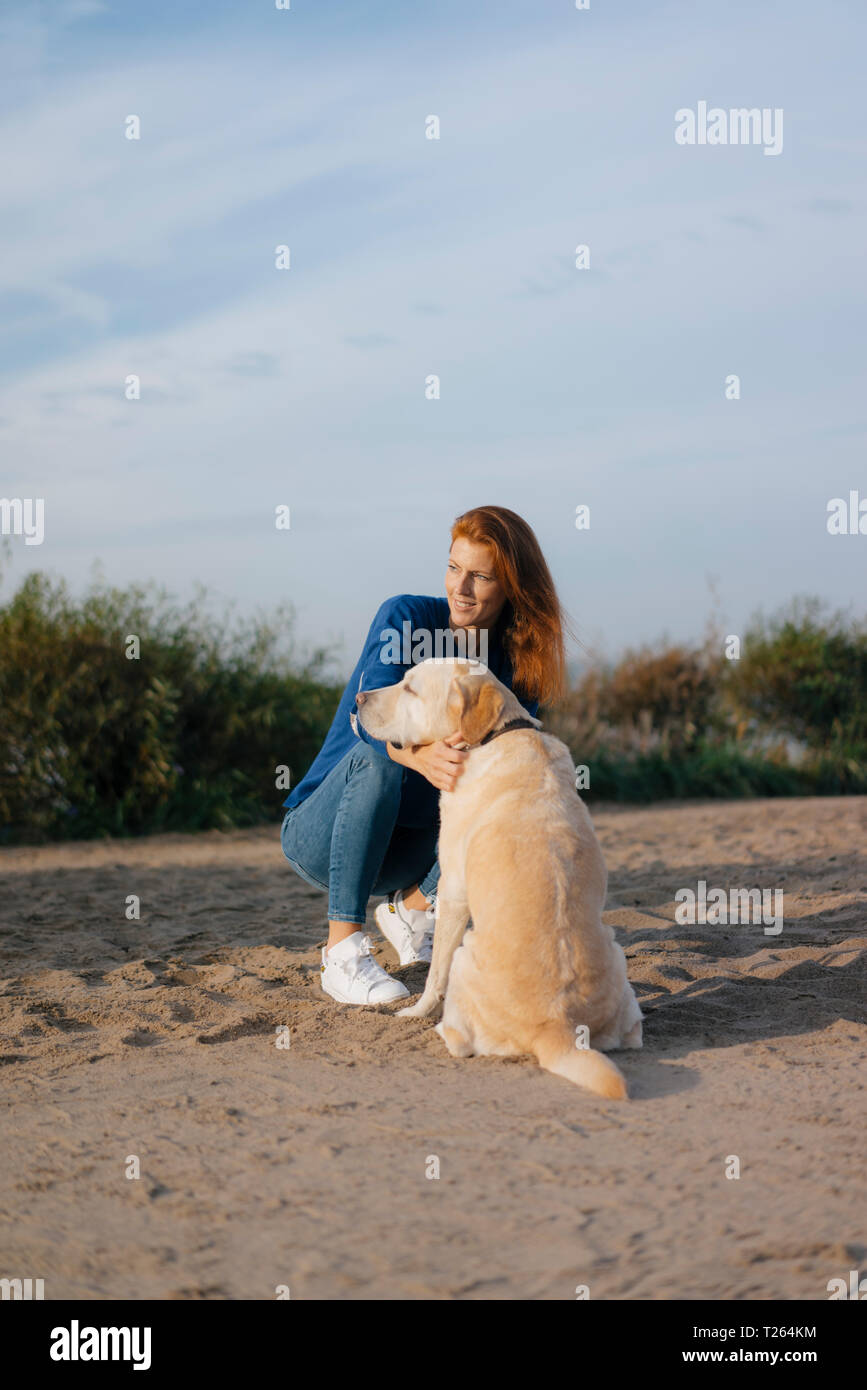 Deutschland, Hamburg, Frau mit Hund am Strand am Elbufer Stockfoto